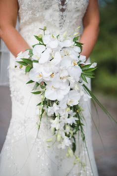 a bride holding a bouquet of white flowers