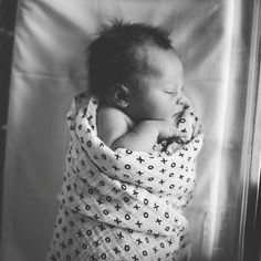 a black and white photo of a baby wrapped in a blanket