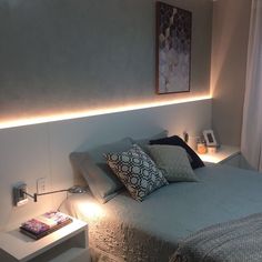 a bed that has some pillows on top of it and lights in the corner next to it