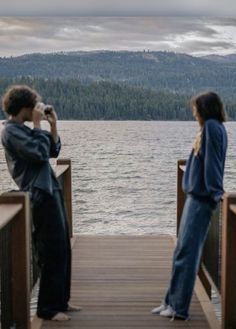 two people standing on a dock taking pictures