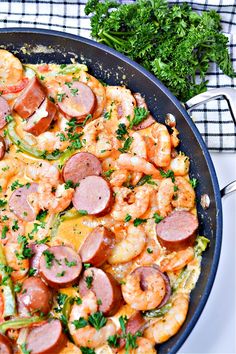 a skillet filled with shrimp, sausage and other foods on top of a table