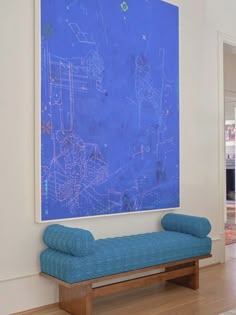 a blue painting hangs on the wall next to a bench