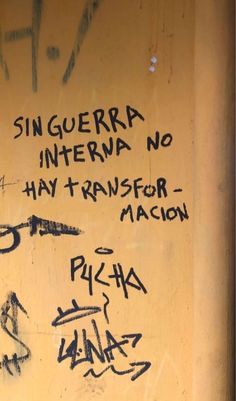 graffiti written on the side of a yellow wall with writing in spanish and other languages