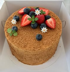 a cake with strawberries, blueberries and raspberries on top in a box