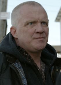 an older man standing in front of a telephone pole and looking off into the distance