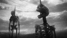 two skeletons standing in front of a cloudy sky