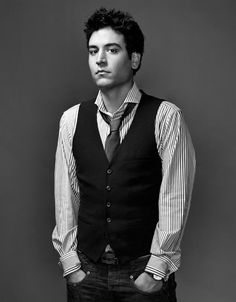 a young man in a vest and tie posing for a black and white photo with his hands in his pockets