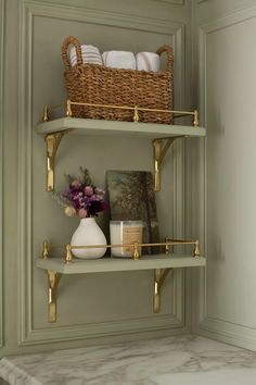 the shelves in the bathroom are decorated with gold and white decor, such as vases