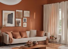 a living room with an orange wall and white furniture in the center, along with pictures on the walls