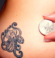 a woman's stomach with an octopus tattoo on it and a penny in the background