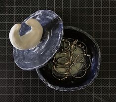 an overhead view of a bowl with some gold rings in it and a hat on top