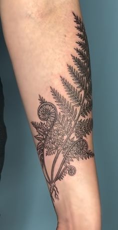 a woman's leg with a tattoo on it that has flowers and leaves growing out of it