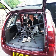 a man sitting in the back of a red car with a camera attached to it