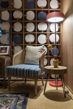 a chair and table in front of a wall with round lamps on it's sides