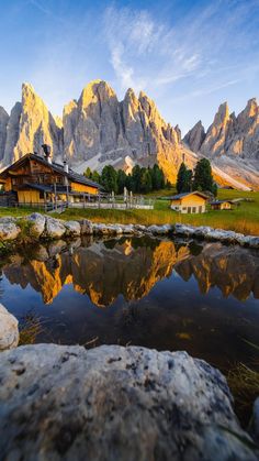 the mountains are reflected in the still water at sunset, with an alpine lodge on the other side