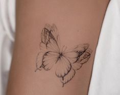 a butterfly tattoo on the back of a woman's left arm is shown in black and white