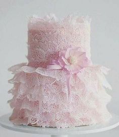 the cake is decorated with pink lace and a large flower on it's side