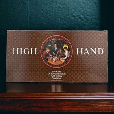 a sign that says high hand on top of a wooden table next to a green wall