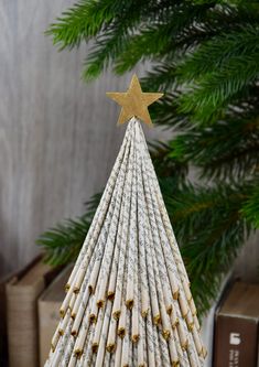 a small christmas tree made out of books with a gold star on top, sitting in front of a bookcase