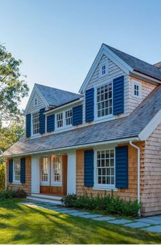 a house that has blue shutters on the front and side of it, with green grass