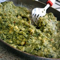 a skillet filled with spinach and cheese on top of a stove next to a spatula