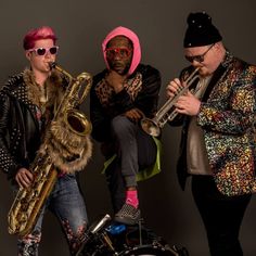 three people are posing for a photo with their instruments and one is playing the saxophone