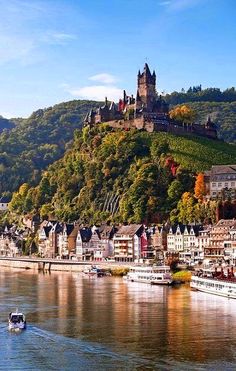 a castle on top of a hill next to a body of water with boats in it