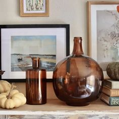 there are many different items on the shelf in front of the pictures and books, including vases