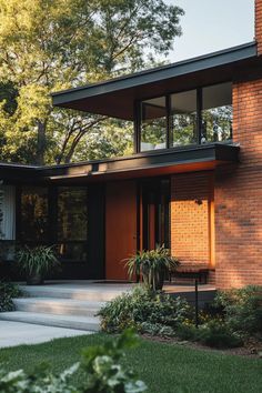 a brick house with large windows and lots of greenery