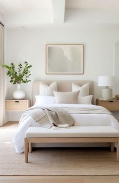 a bed with white linens and pillows in a bedroom next to a painting on the wall