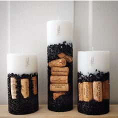 three candles with corks and wine corks on them sitting on a table next to each other