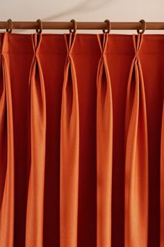 an orange curtain hanging on a wooden rod