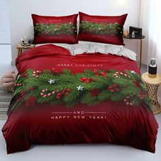 a bed with red sheets and christmas decorations on it, next to a night stand