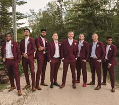 a group of men standing next to each other in front of some trees and bushes