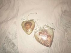 two heart shaped ornaments with pictures on them sitting on a white bedcloth covered sheet