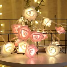 some white and pink roses are on a table with string lights in the shape of hearts