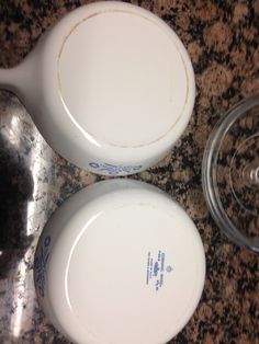 two white dishes sitting on top of a counter next to a glass bowl and spoon