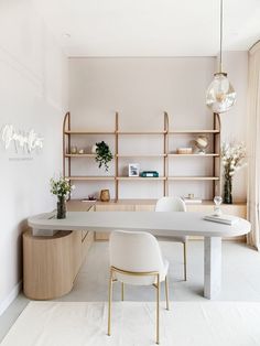 a white table and chairs in a room with shelving on the wall behind it