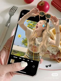 a woman holding up her cell phone to take a picture of herself eating some food