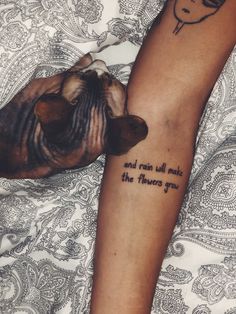 a dog is sitting next to a woman with a tattoo on her arm that says and rain will make the flowers grow