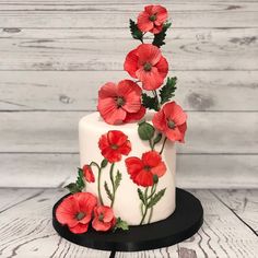 a white and black cake with red flowers on it