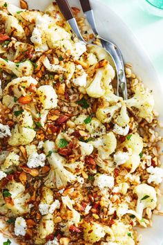 a white plate topped with cauliflower covered in feta cheese and seasoning