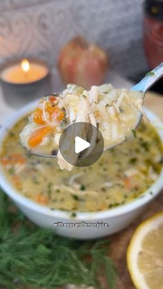 a spoon full of soup sitting on top of a table next to lemon wedges