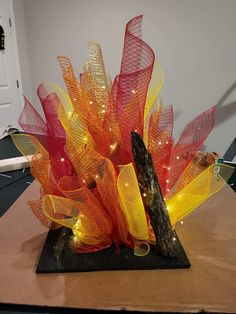 a sculpture made out of glass and lights on a wooden table with a white wall in the background