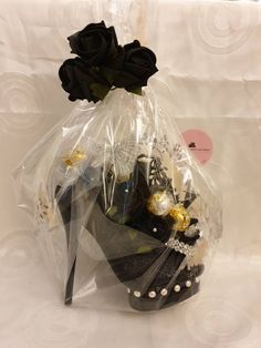 a black shoe is wrapped in plastic and has flowers on the top, along with other items