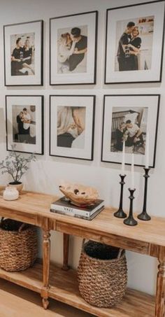 a living room with pictures on the wall and wooden table in front of two vases