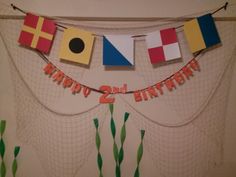 a happy 2nd birthday banner hanging from a net with flags and streamers on it