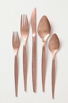 five forks, two spoons and one knife on a white tablecloth with black border