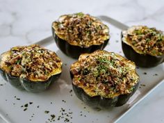 four stuffed acorns on a white plate with seasoning sprinkles