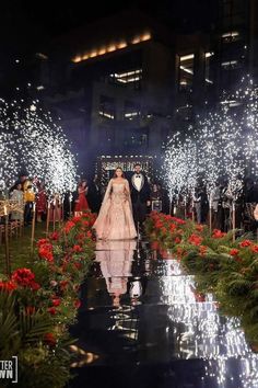 the bride and groom are walking down the aisle with their sparklers in the air